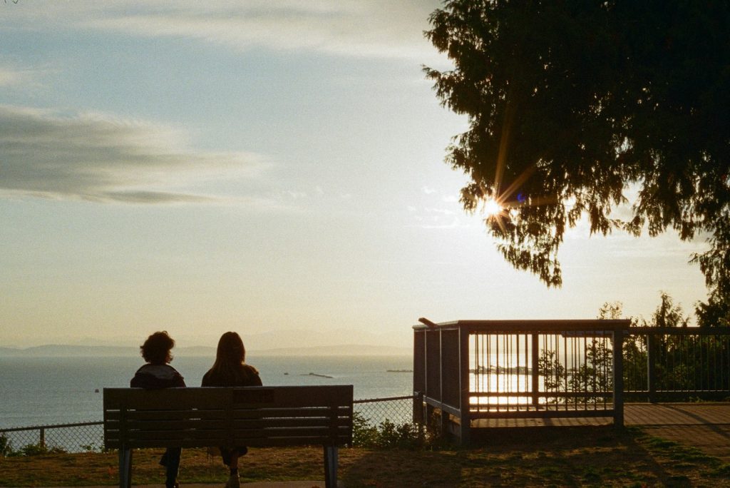 Two people on a bench watching the sunset over the water in Tsawwassen