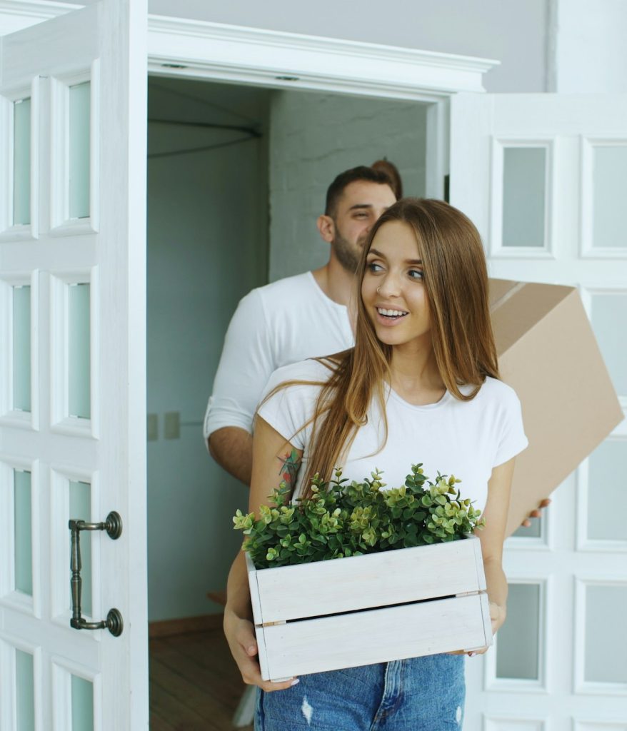 A couple carrying boxes into their new home